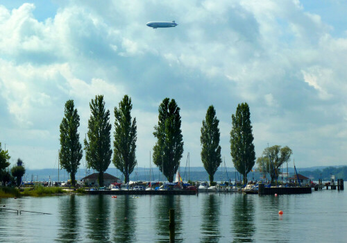 Bodenseelandschaft mit überfliegendem Zeppelin-Luftschiff.

Aufnameort: Unteruhldingen.
Kamera: Panasonic DMC-FZ200