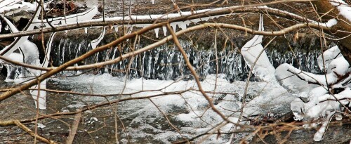 Eine Fließbewegung des Wassers kann durch äußerlich erfolgende Abkühlung zusammen mit Frost auch am Ufer Eisbildungen hervorrufen.
https://de.wikipedia.org/wiki/Eis#Erstarrungsvorgang

Aufnameort: Eiershausen Schwarze Bach
Kamera: Canon EOS 1300D